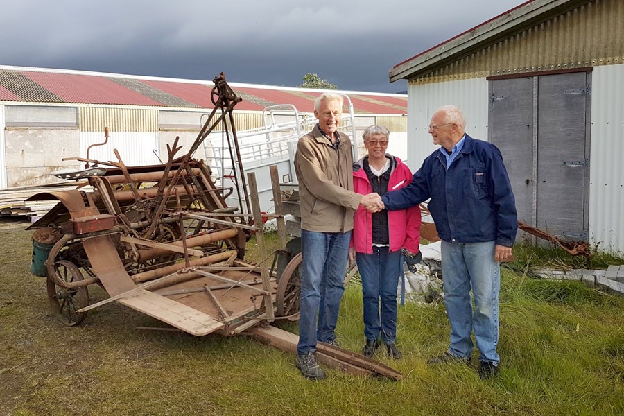 Magnús Sigsteinsson og Marta Guðrún Sigurðardóttir á Blikastöðum afhenda Bjarna Guðmundssyni, verkefnisstjóra á Landbúnaðarsafni Íslands á Hvanneyri, kornskurðarvélina góðu.