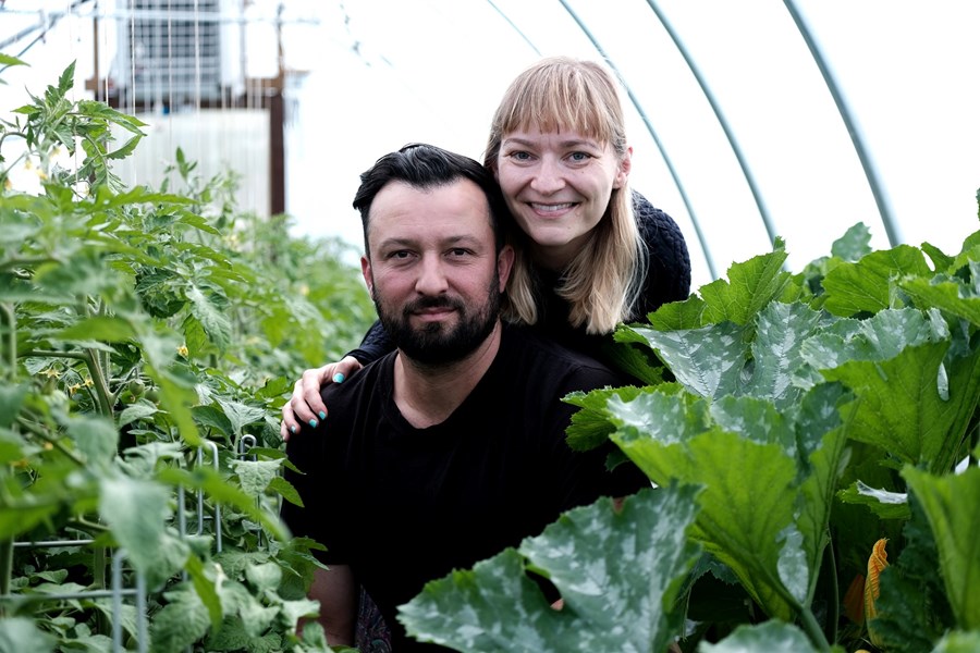 Áslaug og Nicholas í Reykjalundi, með tómata- og kúrbítsplöntur beggja vegna við sig.