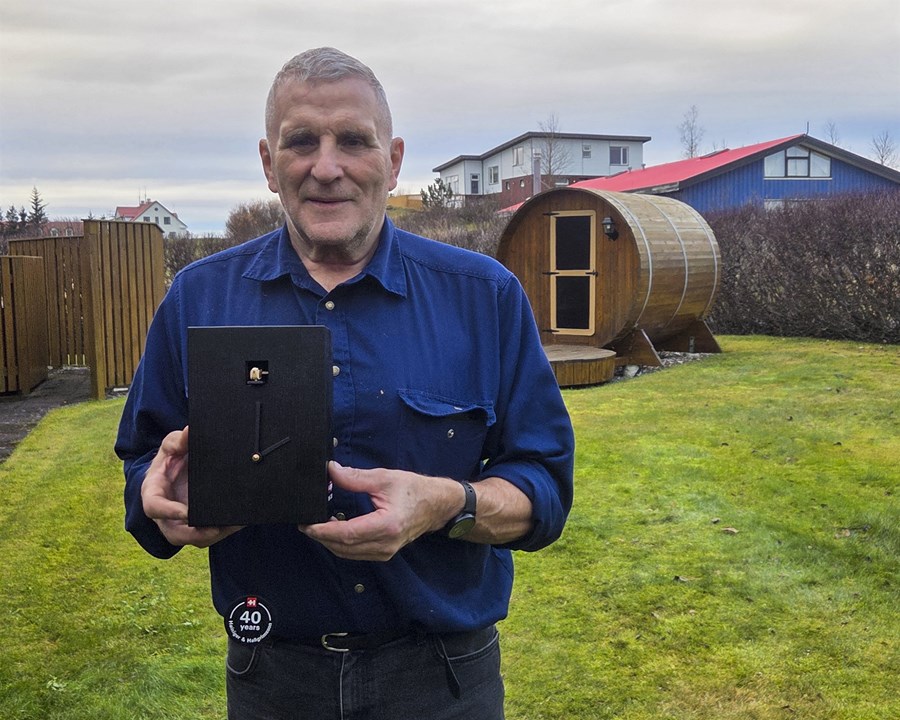 Guðmundur Hallgrímsson frá Hvanneyri hefur selt vörur frá Heiniger í fjóra áratugi. Hér heldur hann á verðlaunum sem hann fékk af því tilefni, en það var handsmíðuð gaukslukka. Niður úr henni er kólfur sem á stendur „40 years – Hallgrimsson & Heiniger“. 