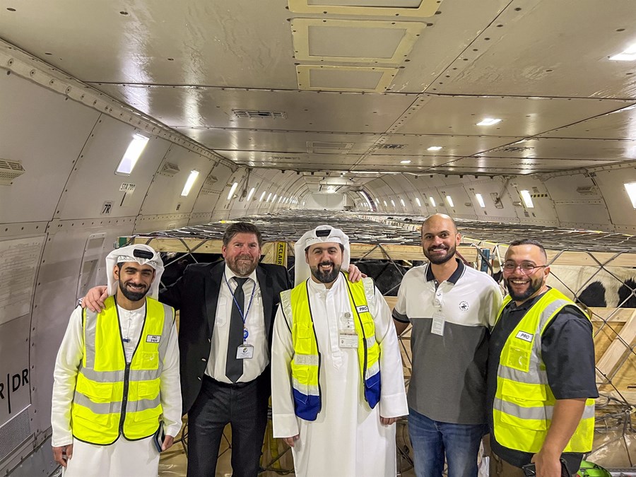 Fjórir heimamenn taka á móti kúnum frá Hermanni Leifssyni í Sameinuðu arabísku furstadæmunum. Aftan við mennina sést inn í fulllestaða flugvél með kúm í kössum sem tryggja öryggi þeirra og halda þeim í litlum hópum. 