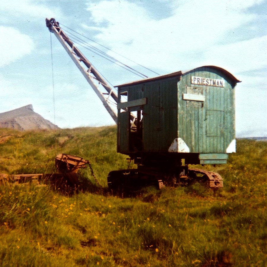 Fyrsta skurðgrafan á Íslandi. Priestman Cub skurðgrafan tók til starfa í Garðaflóa á Akranesi 1. júní 1942, síðar í Innri-Akraneshreppi og Borgarfjarðarhéraði. Veturinn 1943–1944 var grafan lánuð Akranesbæ og notuð sem bryggjukrani við að landa fiski. Gagnsemi gröfunnar reyndist mikil strax frá fyrsta degi. Hún var keypt til landsins að tilstuðlan Þórðar Ásmundssonar, útgerðarmanns á Akranesi og Björns Lárussonar, bónda á Ósi í Skilmannahreppi. Grafan stendur hér við fyrstu viðgerðarþjónustu- skemmu Vélasjóðs í Garðaholti á Akranesi. Myndin er líklega tekin um 1980, en grafan var þá í umsjón Karls Auðunssonar fyrsta, starfsmanns þjónustunnar. Grafan er nú í geymslu hjá Þjóðminjasafni Íslands.