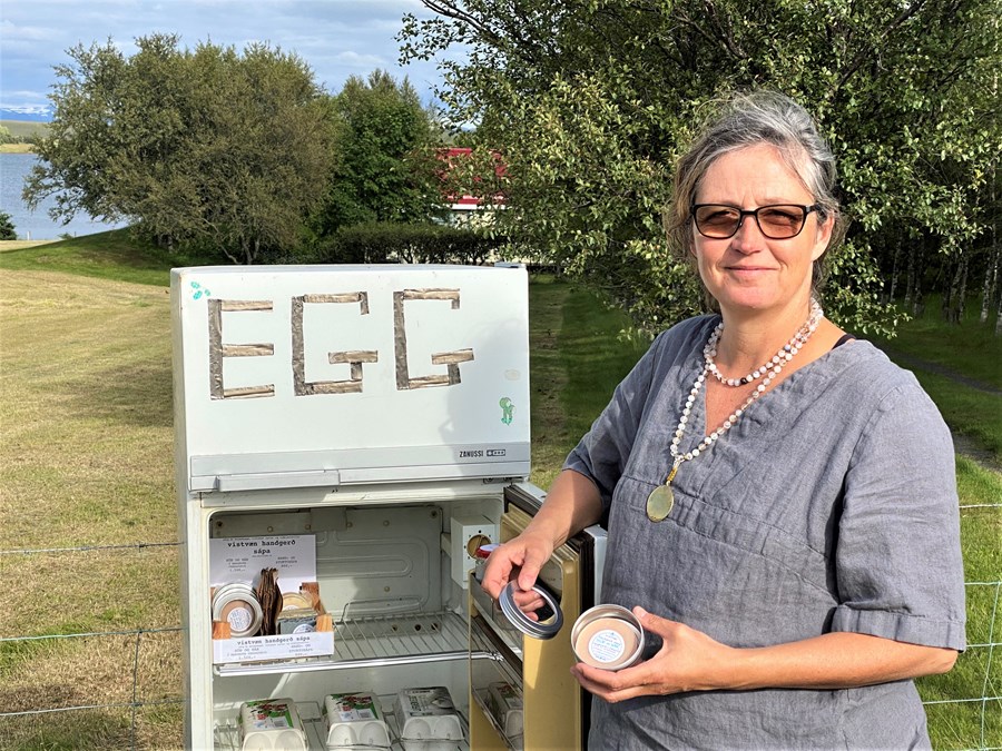 Maja Siska við gamla ísskápinn og sápurnar sínar, sem  hafa slegið í gegn á kórónutímum, auk eggjanna, sem seljast líka vel.